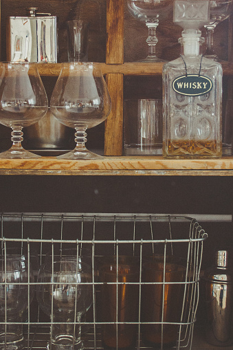 A vintage drink bar stocked with a martini shaker and glasses on wooden crates.