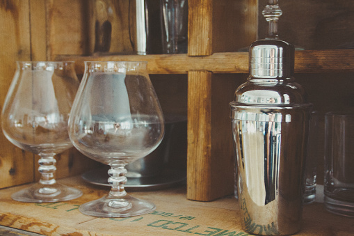 A vintage drink bar stocked with a martini shaker and glasses on wooden crates.