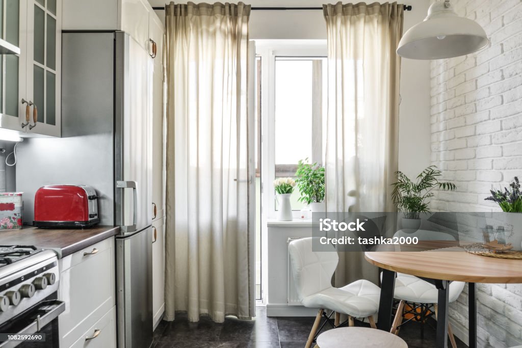 Interior of the kitchen in Scandinavian style Interior of the kitchen in Scandinavian style with white furniture and a dining table. Small Stock Photo