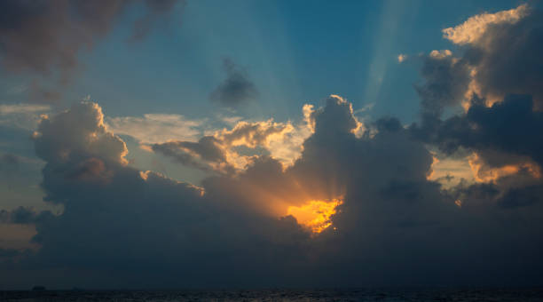istock View a sky with big clouds at sunset with the yellow sun behind projecting rays of light 1082625986