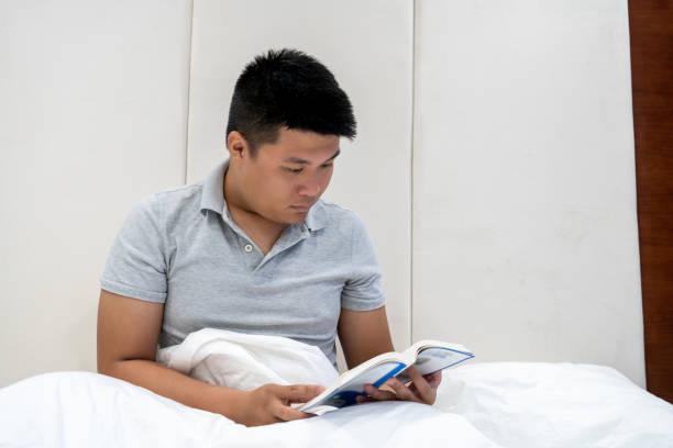 istock Asian man reading book before go to bed 1082638814