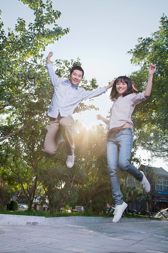 Chinese couple jumping in park