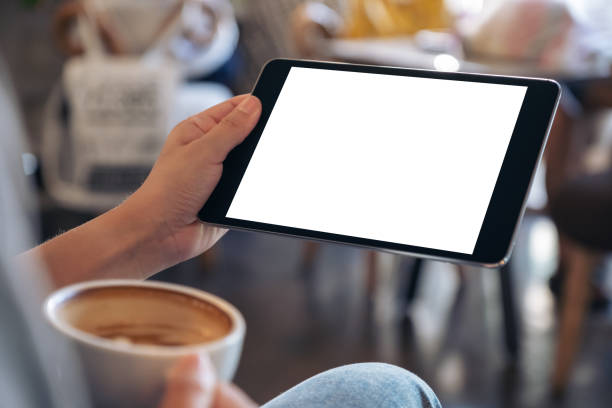 istock Mockup image of woman's hands holding black tablet pc with blank screen while drinking coffee in cafe 1082643462