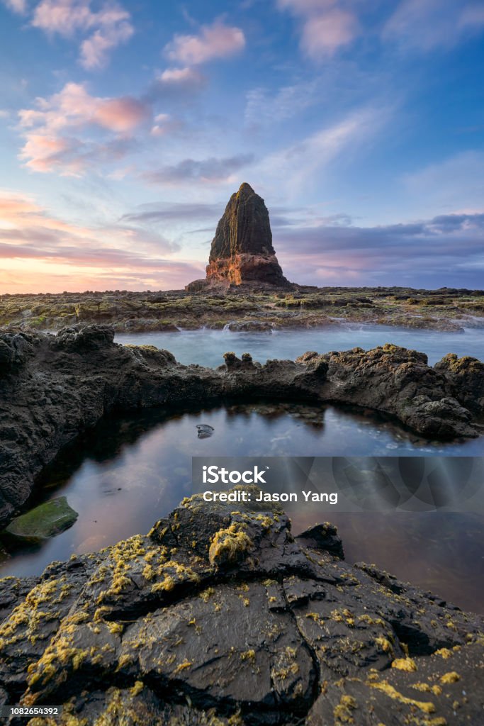 The Sunrise Shot of the Pulpit Rock at Cape Schanck with Water as Forground The breathtaking Pulpit Rock is the favourite spot at Cape Schanck. When lit by the warm morning sun, the rock takes all the attention and becomes a monument in the middle of the sea. Melbourne - Australia Stock Photo