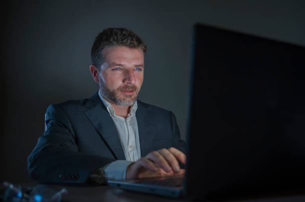 istock young attractive and dedicated workaholic  entrepreneur man working late night using laptop computer trading on forex market or financial business analyzing data isolated on dark background 1082669448