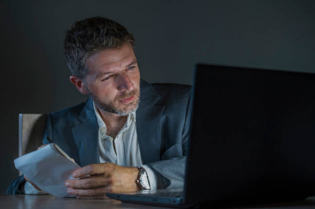 istock young attractive and dedicated workaholic  entrepreneur man working late night using laptop computer trading on forex market or financial business analyzing data isolated on dark background 1082669674