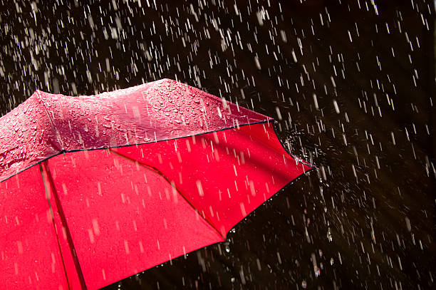 rosso ombrello e pioggia contro sfondo nero - ombrello foto e immagini stock