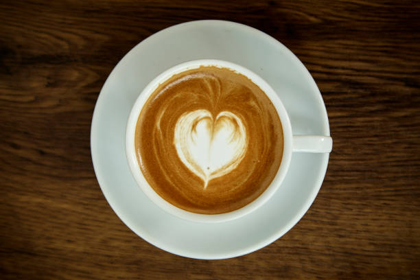 istock A cup of coffee with heart pattern in a white cup on wooden background 1082677236