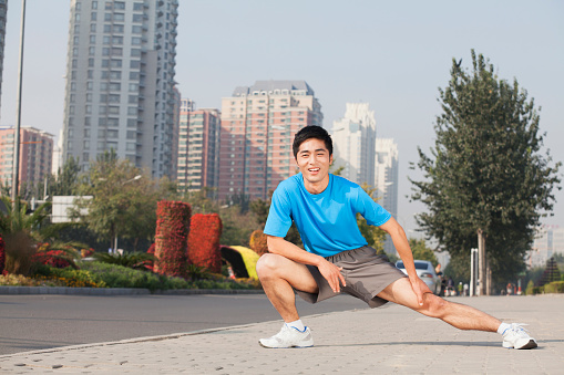 Chinese man stretching in city before exercise