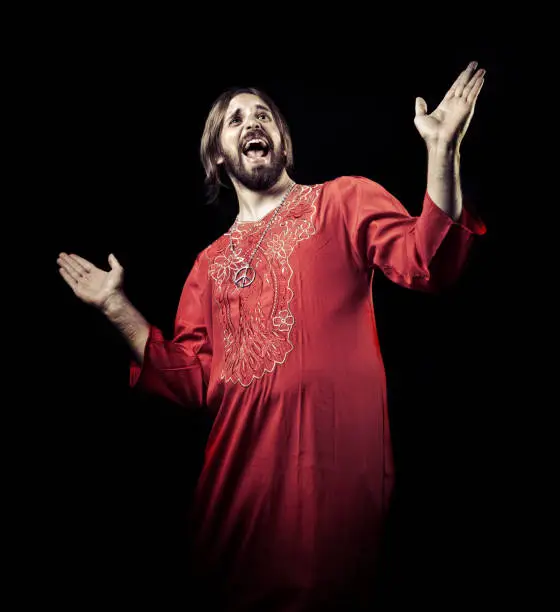 young guy with a guru dress opening his arms in a pose like singing.