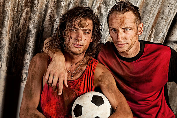 istock Two Young Men Covered in Mud Posing with Soccer Ball 108268246