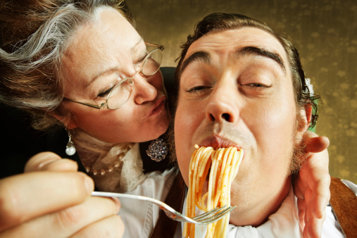 Close-up of a italian mature woman kissing her Son with spaghetti in his mouth