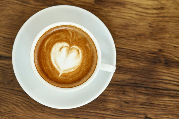istock A cup of coffee with heart pattern in a white cup on wooden background 1082685510