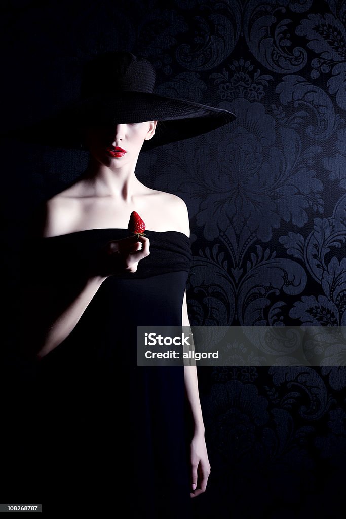 Woman ブラックドレスを着て、帽子と赤の口紅を持つストロベリー - 女性一人のロイヤリティフリーストックフォト