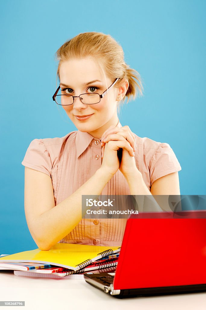 Mujer joven sentado al escritorio con ordenadores portátiles y computadora portátil - Foto de stock de Sólo mujeres libre de derechos