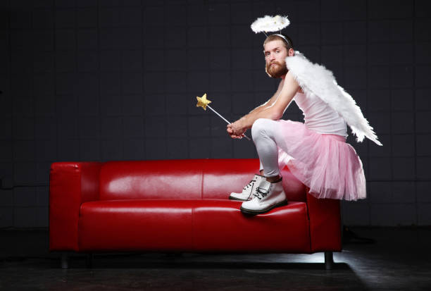 angel: costume man sitting on couch - engelenpak stockfoto's en -beelden