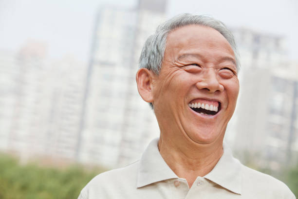 Senior Chinese man laughing in public park