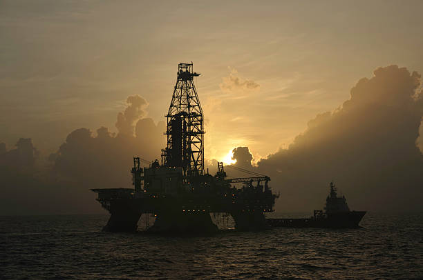 Offshore oil rig with vessel at sunrise stock photo