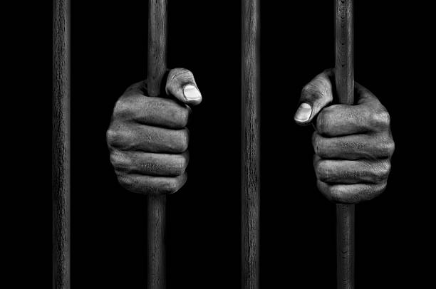 las manos de un preso en barras de celda de prisión - jail fotografías e imágenes de stock