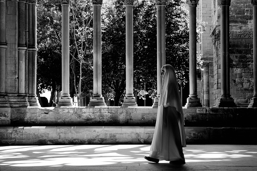 Monja caminando a través de una iglesia habitación Cloister, blanco y negro photo