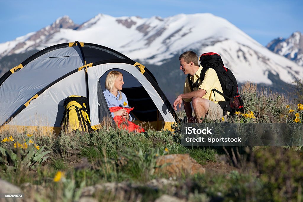 Young Couple With Tent and Backpacks Camping In Colorado Attractive couple camping with snow-covered mountains and blue sky in background. 20-24 Years Stock Photo