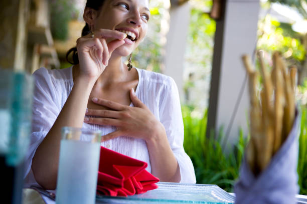 Businesswoman in yellow blazer at lunch break working and eating a take out salad bowl in a park.