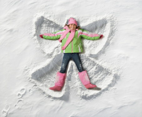 young girl creating Snow Angel in snow. Photographed from directly above.