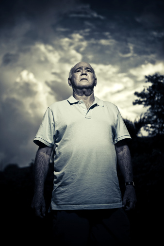 a senior man looking with a sense of despair and worries up to the sky