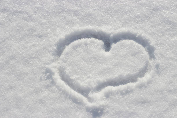 Heart shape drawn on snow close-up view from above, winter background