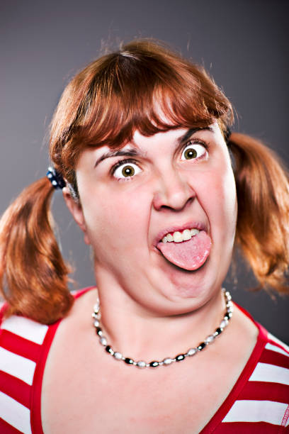 женщина, делая дурачусь лицо высовывать язык - making a face mischief sticking out tongue isolated on red стоковые фото и изображения