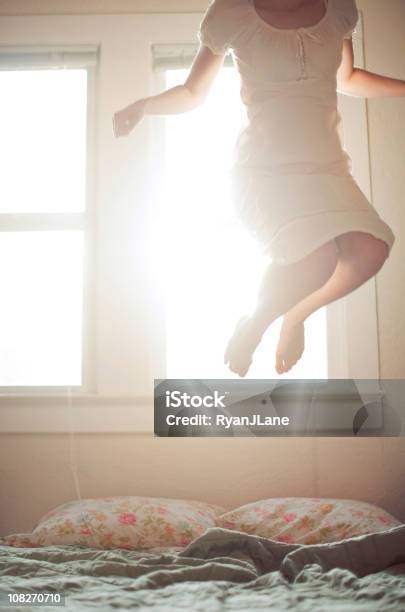 Молодая Женщина Прыжки На Кровати — стоковые фотографии и другие картинки Босиком - Босиком, В воздухе, В помещении