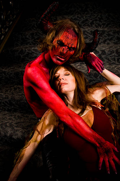 Red Devil Grabbing Woman on Staircase stock photo