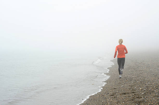 Woman Runner on Foggy Beach stock photo