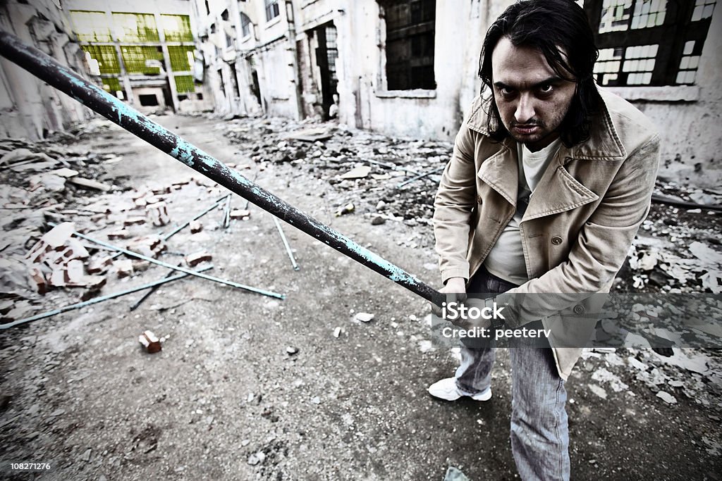 Man in alley holding metal pipe dangerous man ready to hit. Aiming Stock Photo