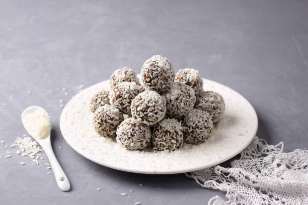 istock Homemade raw date candies with coconut chips on a gray background 1082715814