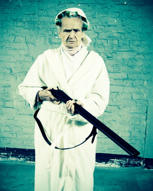 Brave old lady with a shotgun, standing in dressing gown with frown on her face.