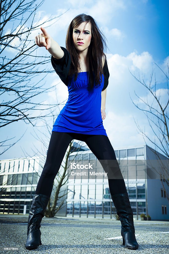 Urban Young Woman Pointing Young woman in front of modern office buildings pointing the way forward. The Avengers - 'Emma Peel' Style, Urban Fashion Portrait. Adult Stock Photo