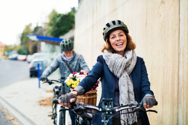 istock Active senior couple with electrobikes standing outdoors on a road in town. 1082718486