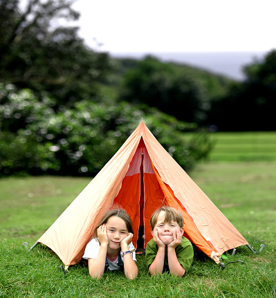 Two children (7&5) lie in the entrance of a small tent