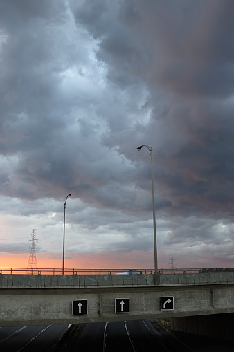 Scenic perspective of an empty highway against a vibrant backdrop of dramatic, colorful clouds during the golden hour