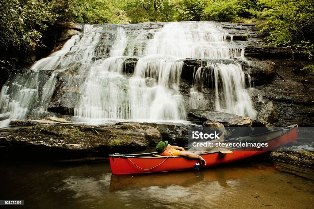 Man in Canoe en la parte inferior de la cascada - Foto de stock de Acostado libre de derechos