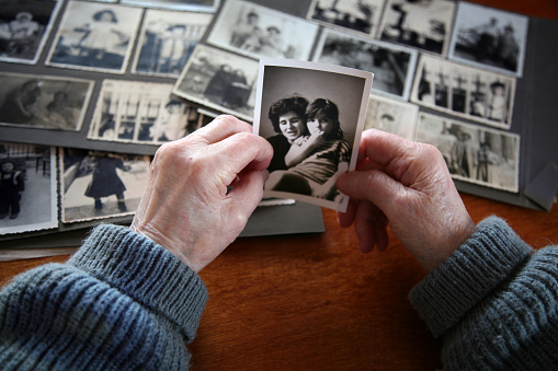 Elderly hands looking at old photos of self and family