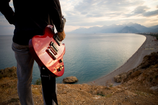 Musician plays the acoustic guitar while sitting on a chair on the beach. Cropped. Faceless. High quality photo