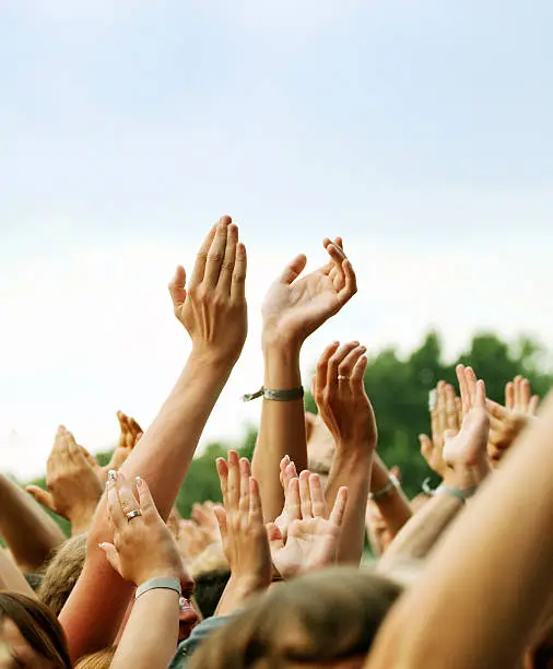 Large party group of people holding their arms and hands high in the air during an Outdoor Concert