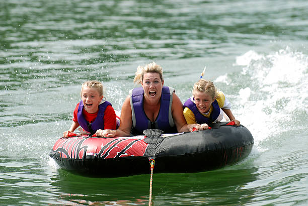 Twins with Mom Riding Tube  fast boat stock pictures, royalty-free photos & images