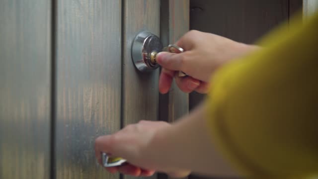 Woman unlocking entrance door with a key. Person using key and locking door. Real estate security concept