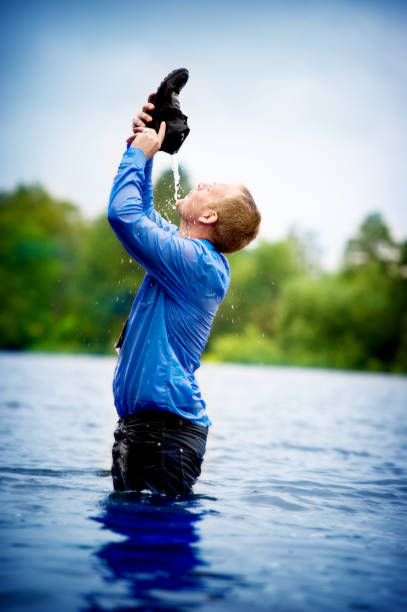 Man drinking out of his shoe standing deep in water  waist deep in water stock pictures, royalty-free photos & images