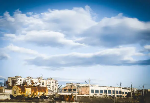 Photo of Post industrial scene with an abandoned train,partially abandoned factory in an old district.