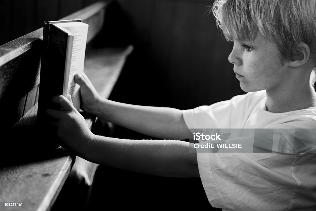 tranquil scene of child in church reading prayer book  Church Stock Photo