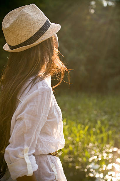 Young girl in the countryside standing by the pond looking out to the late afternoon sun.